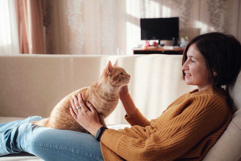 Young woman resting with pet in sofa at home.